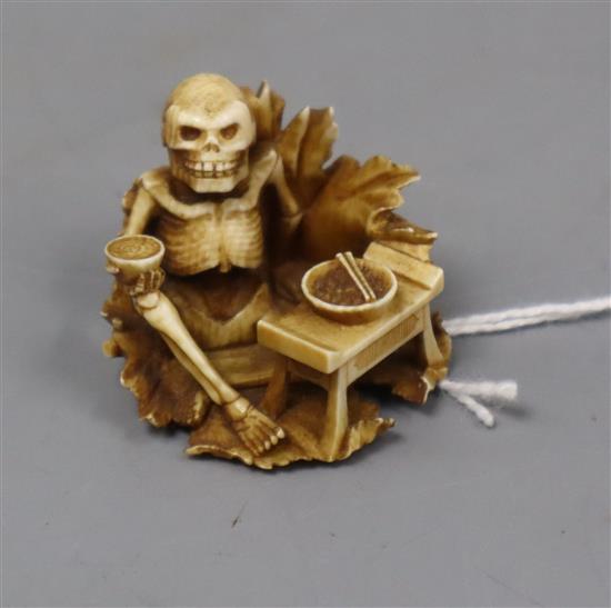 A Japanese ivory netsuke of a skeleton drinking sake